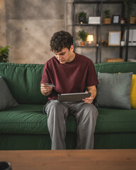 teenager young man sit at home use credit card shopping online