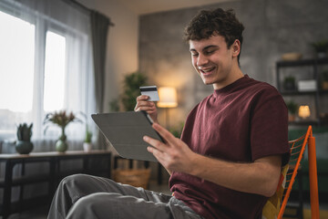 teenager young man sit at home use credit card shopping online