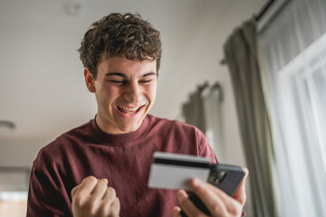 teenager young man sit at home use credit card shopping online
