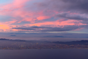 Beautiful sunset over the sea and the city in the background . Awesome twilight over the mountains
