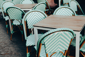 Pale green color chairs on cafe, restaurant terrace. Empty seats, tables on the old town street....
