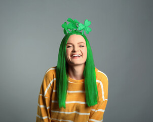 St. Patrick's day party. Pretty woman with green hair and clover headband on grey background