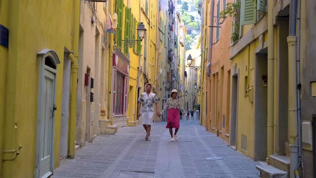 colorful old town of Menton on the French Riviera France during sunset. A diverse couple of men and women visiting Menton France Europe during the European summer, couple walking in old city of Menton