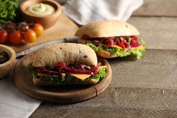 Delicious sandwiches with bresaola, lettuce and cheese on wooden table. Space for text
