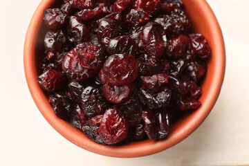 Tasty dried cranberries in bowl on light table, top view