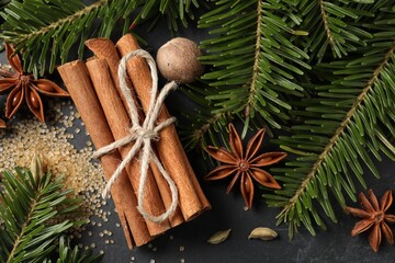 Different spices, nut and fir branches on gray table, flat lay