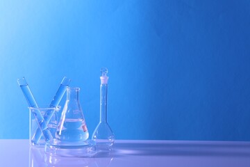 Laboratory analysis. Different glassware on table against light blue background