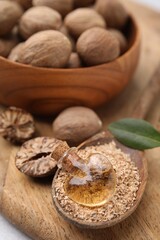 Nutmeg essential oil, whole and ground nuts on wooden board, closeup