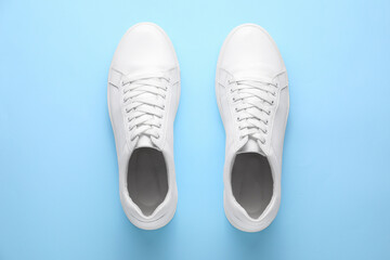 Pair of stylish white sneakers on light blue background, top view