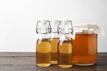 Homemade fermented kombucha in glass jar and bottles on wooden table. Space for text