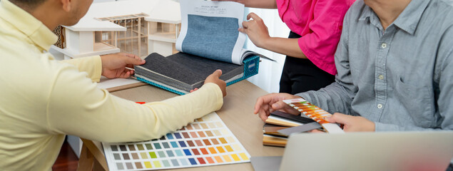 Skilled interior design team carefully selecting curtain materials while coworker selecting the...