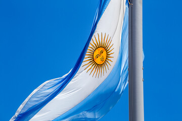 Argentine flag flying on a flagpole against a blue sky on a sunny day. Patriotic symbol of...