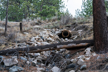 Highway culvert pipe outlet underneath road with rocks below.