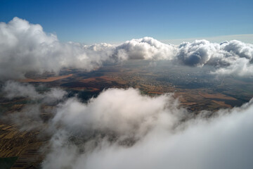 Aerial view at high altitude of earth covered with puffy cumulus clouds forming before rainstorm