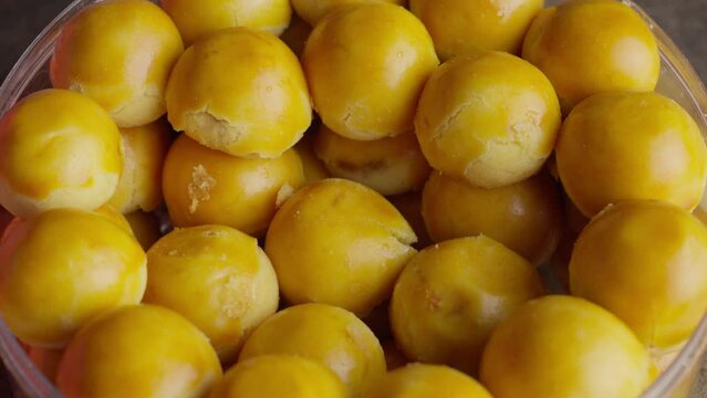 Indonesian pineapple filled cookie tart or nastar in bowl picked up by single hand, static