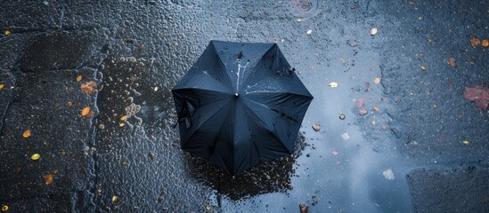 Copy space available for flat lay of rain season with natural background of wet asphalt and a reflection umbrella in a puddle.
