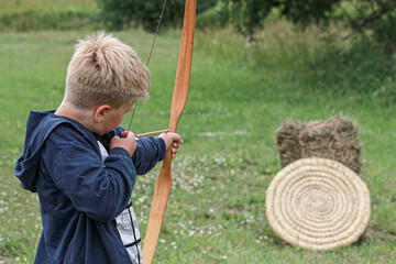 boy shooting with a bow, view from the back
