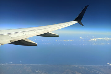 View through airplane window of commercial jet plane wing flying high in the sky. Air travelling concept