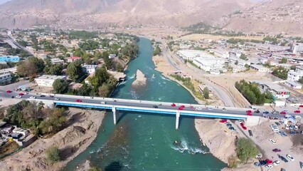 An aerial shot of two bridges crossing a river in a village, with cars crossing the bridge. The location is Faizabad, Badakhshan, Afghanistan.
