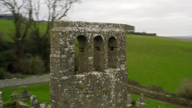 Drone orbits around weathered bell tower of concrete bricks with no bell