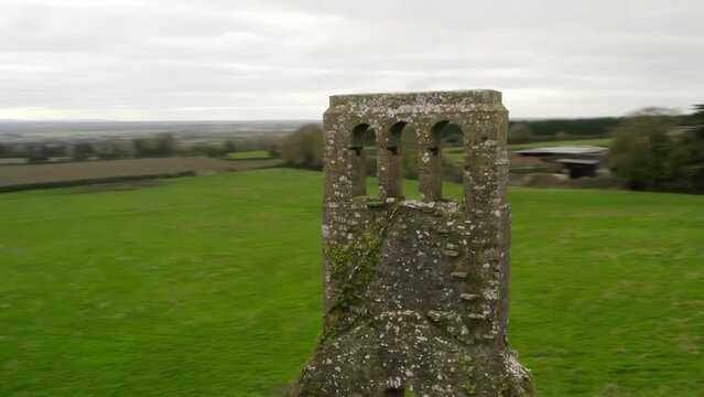 Fast orbit parallax around thin brick bell tower of remnant church in Irish countryside