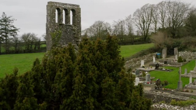 Reveal of old scenic graveyard from behind tree with lush green pastures