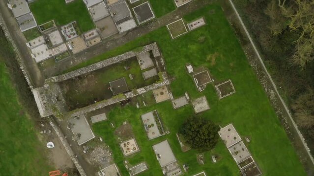 Drone zenithal top down view rotates above cemetery plots and old church walls