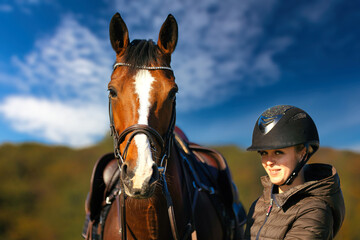 Fototapeta premium Horse head portraits in front of a blue sky and a rider standing next to it..