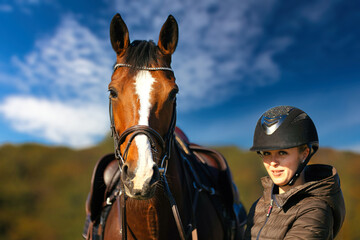 Obraz premium Horse head portraits in front of a blue sky and a rider standing next to it..