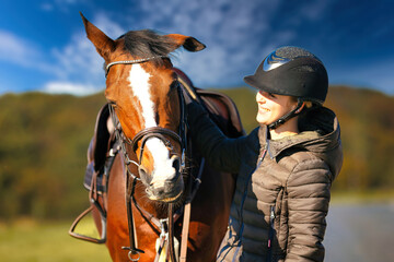Fototapeta premium Horse head portraits in front of a blue sky and a rider standing next to it..
