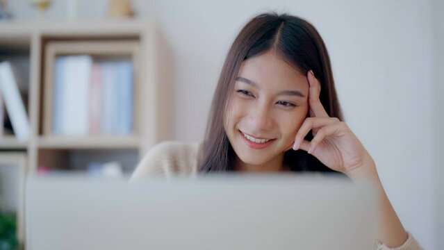 Young asian woman working at home. Happy female using computer laptop on desk at house