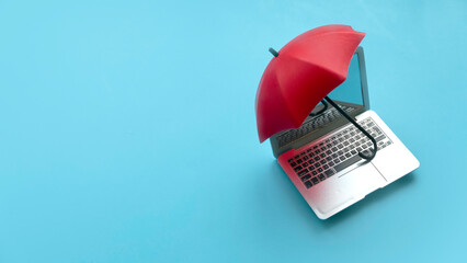 Computer and network security concept. Red umbrella cover the laptop over a blue background.