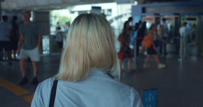 Woman walking strolling through city subway. Back tracking shot. Woman pedestrian walking strolling along metro subway city town. Back of woman walk around big busy large city. City life concept