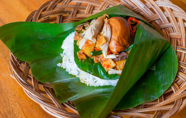 Rice with various side dishes in it, usually called nasirames in Indonesia. served in a place made of babu and covered with banana leaves © Stora Space