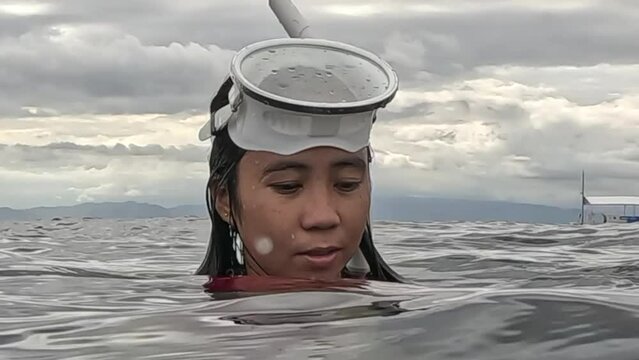 young asian woman with white vintage dive mask and snorkel on ocean surface