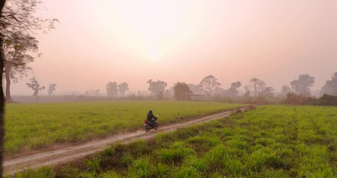 Nepali bike rider rides on trails of Terai region of Nepal with greenery around landscape in golden hour, Drone shot cinematic adventurous and heroic filmy shot 4K