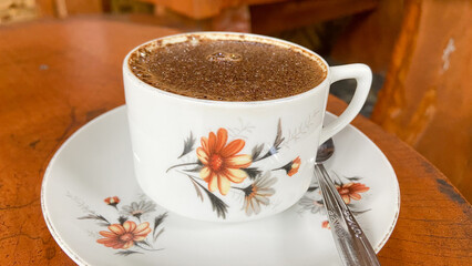 a cup of excelsa coffee on old wooden background. Traditional white cup of Indonesia. Banyuwangi coffee