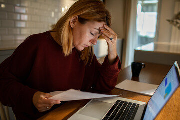 Worried young woman going over bills and home finances at home