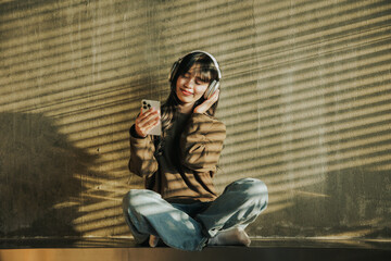 Young Asian woman listening to music and reading a book in a cafe