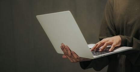 Professional hacker in dark room with laptop sitting at table, closeup