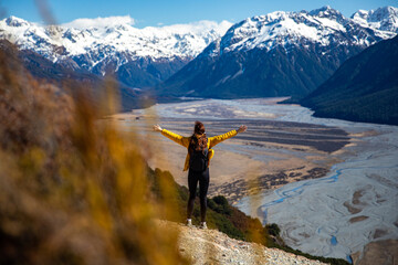 pretty hiker girl admiring the panorama of waimakariri river valley and snow capped mountains in arthur's pass national park from the bealey spurt track