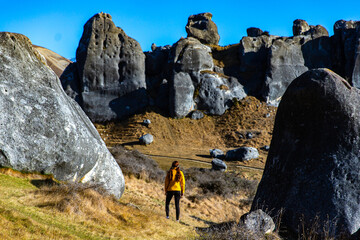 hiker girl walking among unique rock formations at castle hill conservation area near arthur's pass in new zealand alps; unique scenery in catnerbury mountains