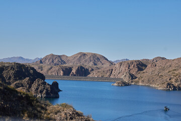 view of a raft sailing over the los reyunos reservoir and surrounded by mountains on a sunny day