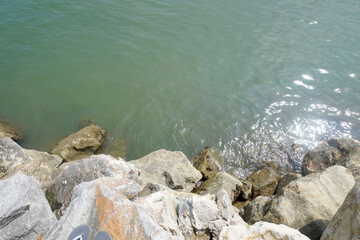 The sea is bordered by large breakwater rocks. sea and rock background. Breaking sea waves on the beach. sea view background concept
