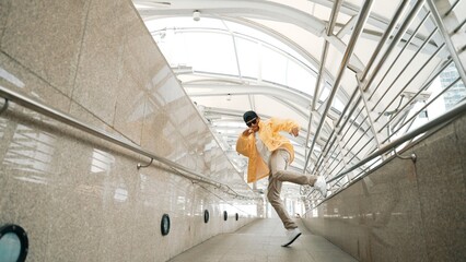 Skilled happy asian hipster walking while dancing in narrow corridor. Close up of break dancer...