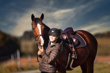Fototapeta premium Horse stands with his rider on a meadow in the sun ready to ride out.