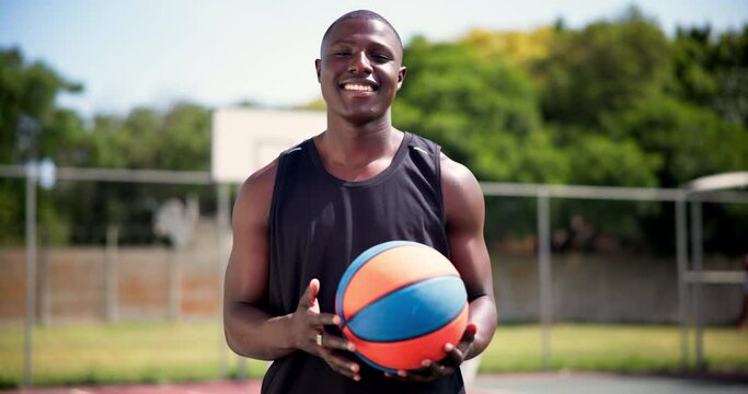 Athlete, face or happy with basketball on court, confident or training with players for competition. Black man, smile portrait and sport professional with talent in game and defender position in team