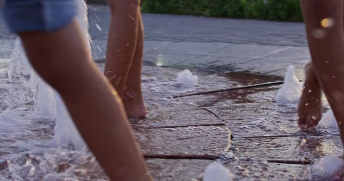 Feet of people walking on a fountain in the park on a summer day
