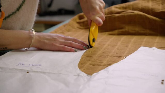 Seamstress using rotary cutter to cut cloth with sewing patterns