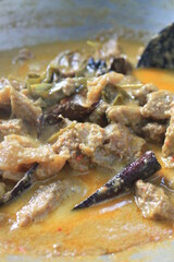 The process of cooking rendang in a traditional stove uses charcoal